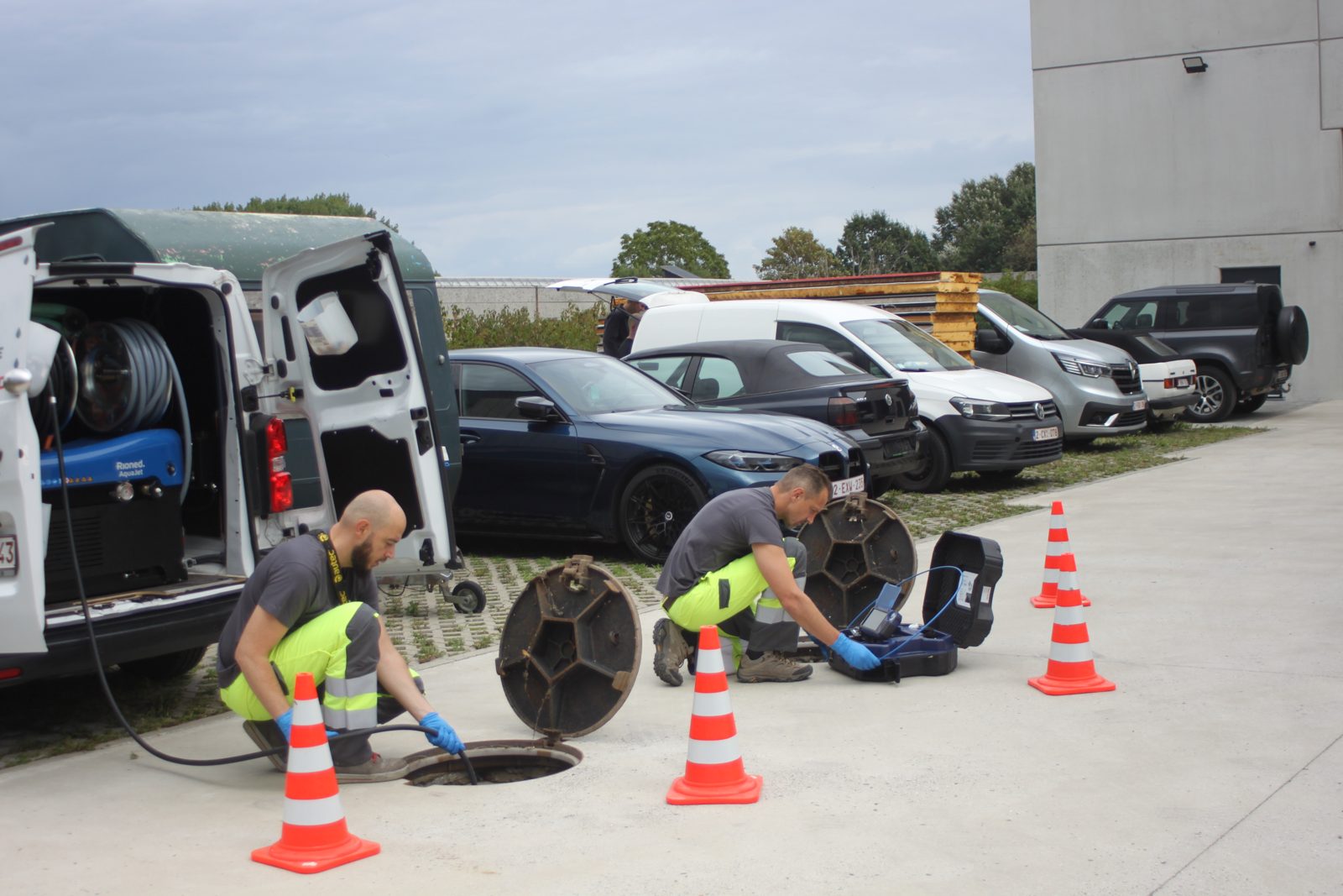 Techniciens HB Débouchage réalisant une inspection caméra dans une chambre de visite, avec camionnette hydrocureuse